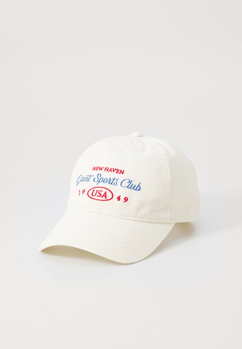 White cotton cap featuring embroidered text in red and blue: "New Haven Gant Sports Club USA 1949." Curved brim with stitched detailing.