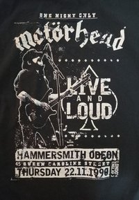 Músico tocando la guitarra y cantando en un micrófono, el texto dice "Motörhead En Vivo y a Todo Volumen, Hammersmith Odeon, 22.11.1990, Londres."