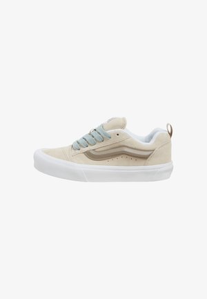 Sneaker in suede beige con lacci azzurri chiari, suola bianca e dettagli color beige. Caratterizzato da punta rotonda e piccole perforazioni sul lato.