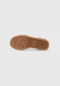 Suela de goma de una zapatilla que muestra patrones de tracción circulares y triangulares con el logo de "Steve Madden" en el centro.