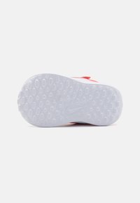 Semelle de sneaker blanche avec un motif de grip texturé, comportant des treads circulaires et un logo Nike visible. Fini lisse avec une légère courbure.