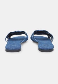Tongs en denim bleu avec un dessus en tissu doux, semelle plate et deux sangles réglables pour un maintien sécurisé. Semelles intérieures texturées pour le confort.