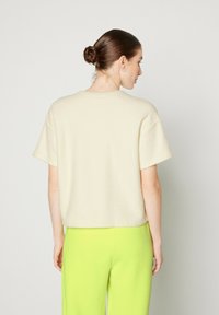Top corto color crema con una finitura testurizzata, abbinato a pantaloni a gamba larga verde brillante. Design semplice con una vestibilità comoda.
