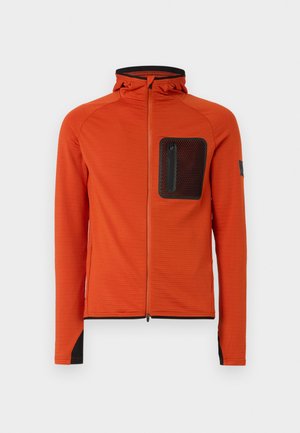 Orange zip-up jakke med struktureret stof, der har hætte, en sort mesh brystlomme og sorte detaljer ved manchetten og kanten.