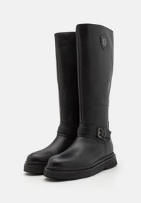 Botas altas de rodilla impermeables negras con un acabado de cuero suave, correa decorativa con hebilla y suela de goma texturizada para mayor agarre.
