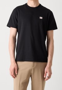 Czarna koszulka z krótkim rękawem wykonana z bawełny. Posiada małą naszywkę z logo na piersi. Prosty, klasyczny okrągły dekolt i prosty dół.