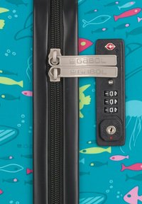 Una maleta color aqua con un patrón de peces, con un zipper negro, etiquetas GABOL duales y una cerradura de combinación de seguridad en el lateral.