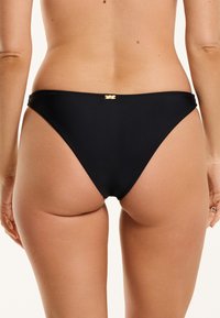 Fekete bikini alsó, alacsony derekú szabással, sima textúrával és egy kis arany logóval a hátsó részen.