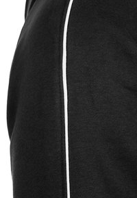 Tissu de sweat-shirt noir à texture lisse, avec une bande verticale blanche sur le côté pour créer un contraste.