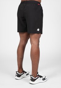 Zwarte shorts met een elastische tailleband en zijzakken, voorzien van een wit gorillalog en gemaakt van een gladde, lichte stof.