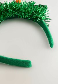 Grøn pandebånd med glittermateriale, der har en blød filtbase og en pom-pom detalje. Designet i en buet form for komfortabel brug.