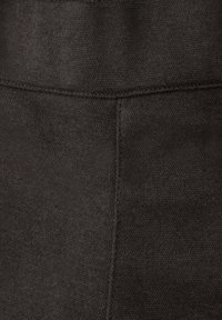 Tmavá texturovaná látka ukazuje detail prošitého švu s jemným rybí kostí vzorem a hladkým povrchem.