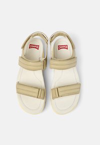 Beige Sandalen mit zwei verstellbaren Riemen, gepolsterten Innensohlen und einer strukturierten Sohle. Mit einem roten Camper-Logo auf der Innensohle gestaltet.