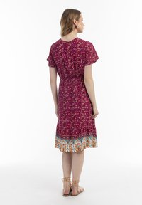 Rochie florală mov cu mâneci scurte, talie elastică și tiv în straturi, având un bordaj floral colorat. Pură cu sandale bej cu barete.