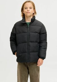 Svart polstret jakke med høy krage, glidelåslukking og elastiske mansjetter. Glatt stoff med horisontale quiltede seksjoner og sidelommer.