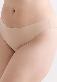 Beige naadloze bikini onderbroek met een gladde textuur en een lage taille. Beschikt over een minimale tailleband en geen zichtbare beenelastiek.