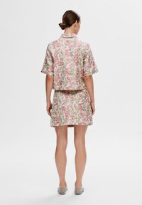 Veste à manches courtes à motif floral et jupe assortie dans des tons de rose et de vert ; tissu lisse, design court et coupe décontractée.