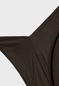 Gros plan sur un tissu marron foncé avec des coutures détaillées formant une forme triangulaire, probablement partie d'un vêtement ou d'un accessoire.