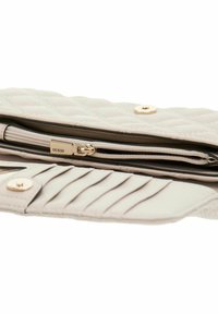 Portefeuille matelassé beige clair avec une texture lisse, quincaillerie dorée, compartiment zippé et emplacements pour cartes avec un détail de couture verticale.