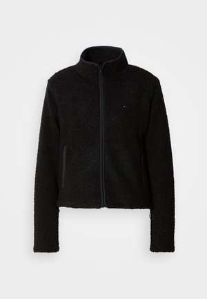 Jachetă din fleece neagră cu guler înalt și fermoar complet, dotată cu două buzunare laterale și un material texturat, ideală pentru căldură.