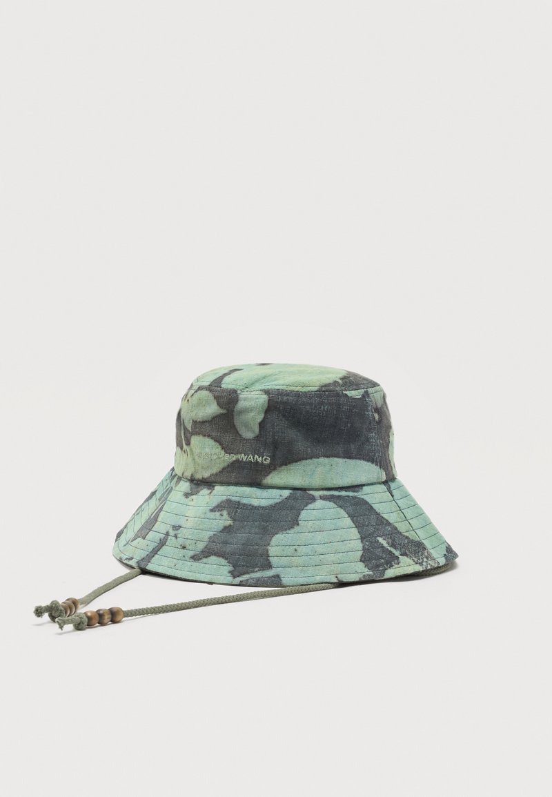 Πράσινο και μαύρο καπό τύπου bucket με ρυθμιζόμενο κορδόνι στο πηγούνι και ξύλινα χάντρες, με διακριτικό κείμενο της μάρκας στο πλάι.