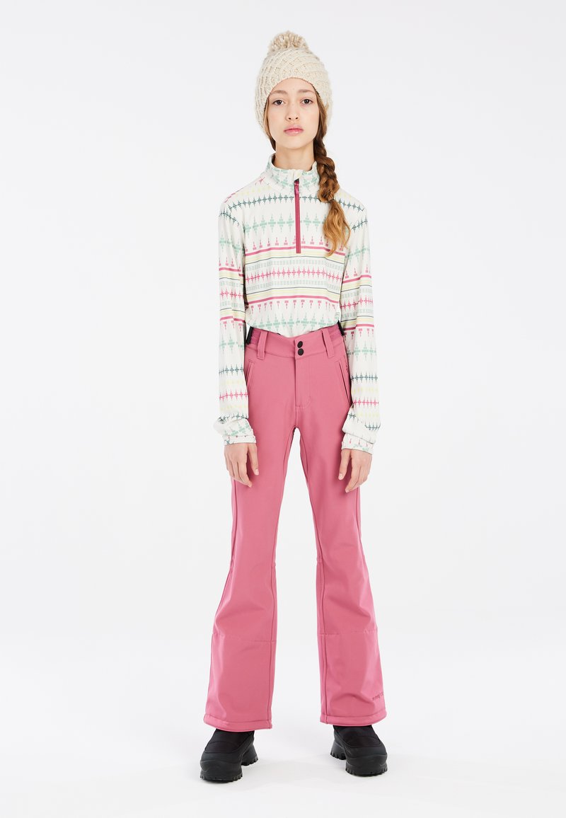 Pull à manches longues, zippé, avec un motif géométrique dans des couleurs pastel, associé à un pantalon de neige rose, évasé, et des bottes noires et robustes.