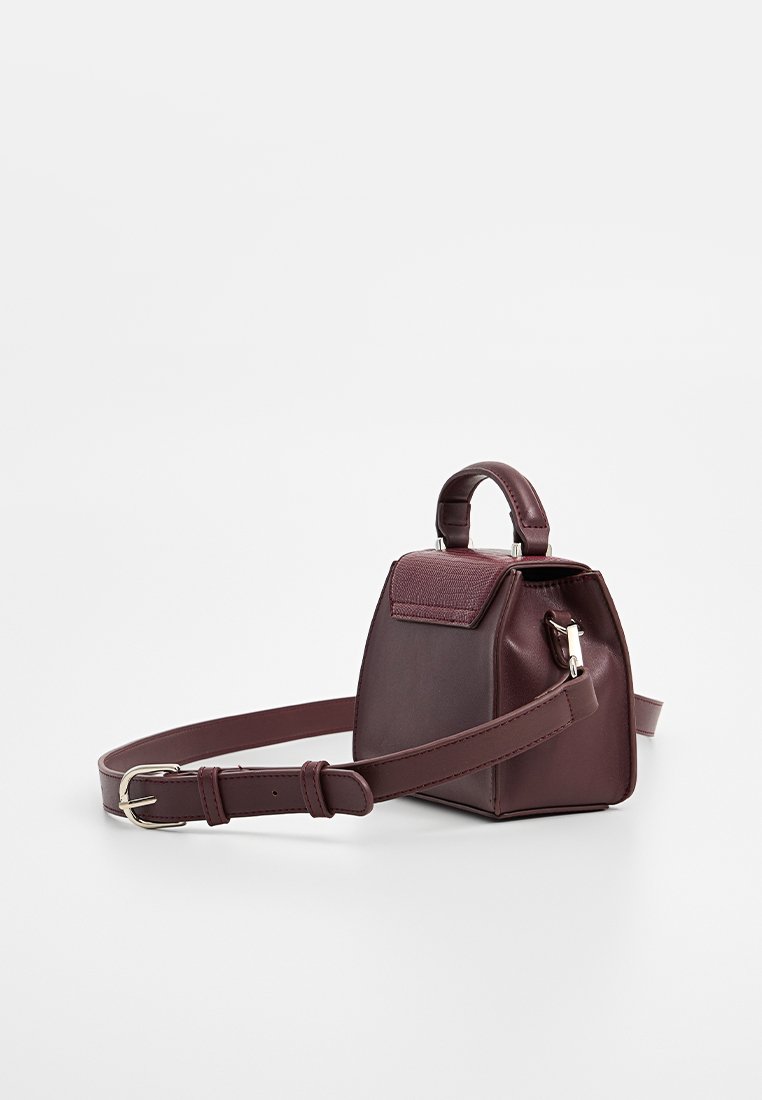 Petit sac à main en cuir maroon avec une forme structurée, une poignée supérieure, une sangle ajustable et un accent texturé sur le rabat. Détails en métal argenté.