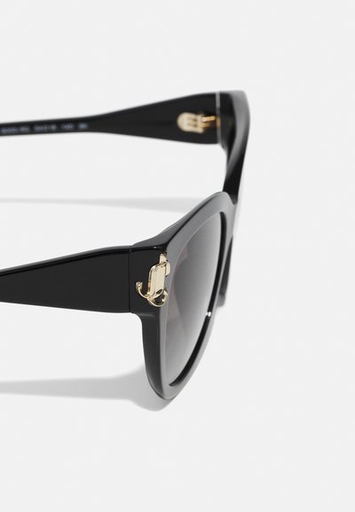 Lunettes de soleil noires avec une finition brillante, des montures angulaires, des verres dégradés sombres et un accent doré sur les tempes.