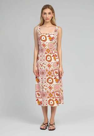 Robe maxi en tissu beige clair avec un décolleté carré, des motifs floraux et géométriques en rouge, orange et rose. Silhouette évasée.
