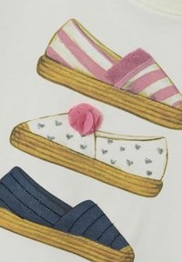 Illustration af tre par sko: lyserøde stribede, hvide med hjerter og marineblå med syede linjer. Hver har en træsål og stofdetaljer.