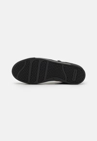 Suola di scarpa in gomma nera con un motivo di grip testurizzato. Presenta scanalature per flessibilità e comfort; contrassegnata con la taglia 37.