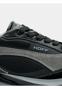 Baskets présentant un mélange de matériaux gris et noirs, incluant du mesh et du suède. Affichent le texte "HOFF" et des accents texturés. Lacets noirs.