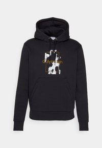Felpa nera con cappuccio e cordoncini, tasca frontale a sacco e logo astratto di Calvin Klein in bianco e oro al centro del petto.