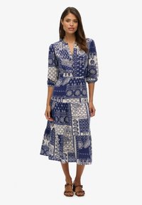 Das navyblaue gemusterte Kleid hat ein mittellanges Design, eine Knopfleiste vorne und dreiviertel lange puffärmel mit einem fließenden Rock.