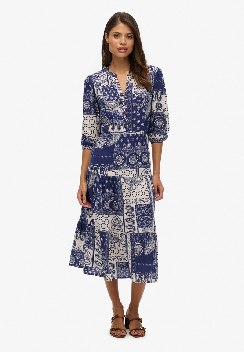 Das navyblaue gemusterte Kleid hat ein mittellanges Design, eine Knopfleiste vorne und dreiviertel lange puffärmel mit einem fließenden Rock.