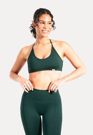 Reggiseno sportivo verde scuro con scollo a cucchiaio e spalline sottili, abbinato a leggings verde scuro a vita alta con motivo strutturato.