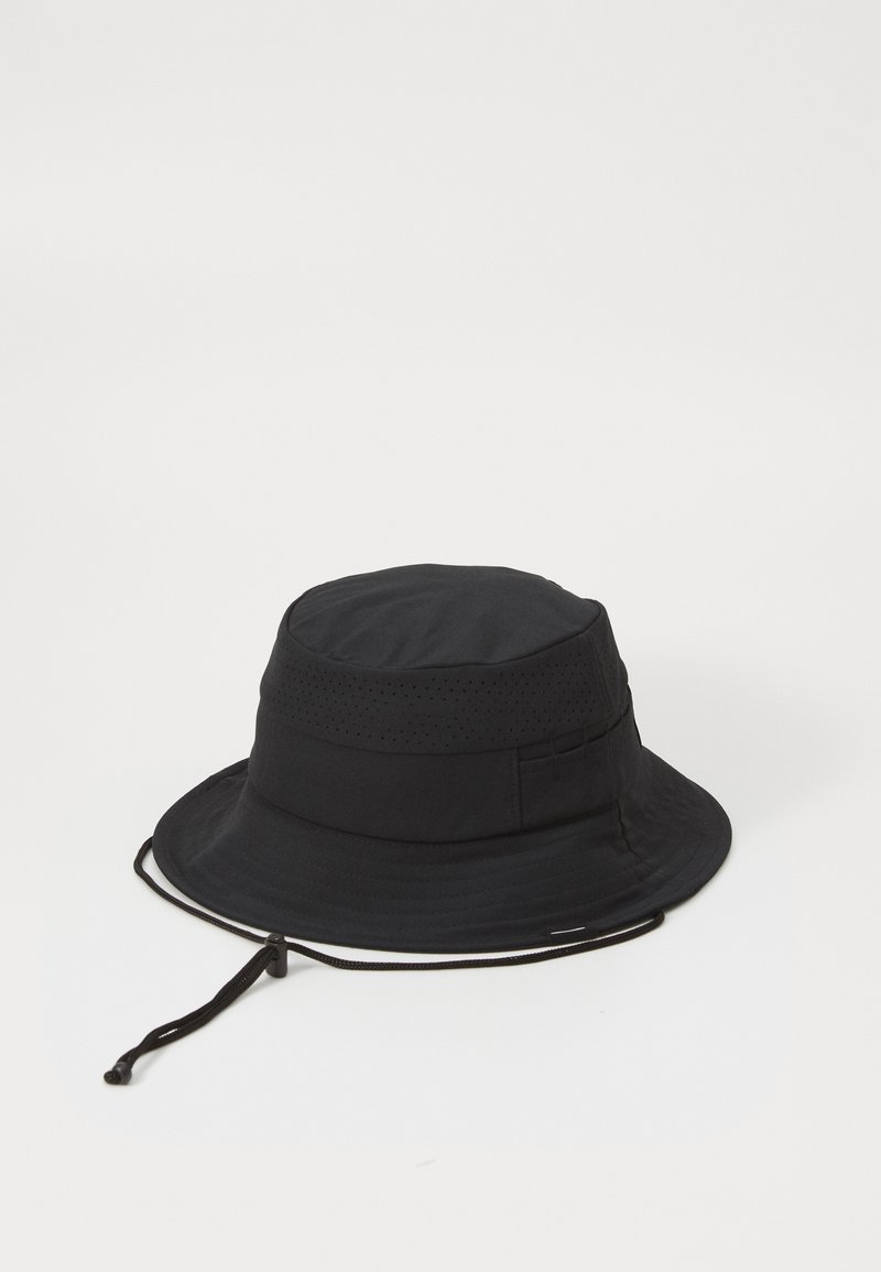 Fekete, légáteresztő anyagból készült sapka, perforált szalaggal, állítható zsinórral és széles, lapos karimával a napvédelem érdekében.