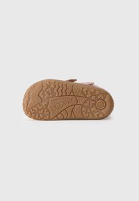 Talpă din cauciuc maro cu un model de textură pentru aderență, prezentând marca "Froddo". Partea superioară de culoare roz deschis cu un design cu curea ajustabilă.