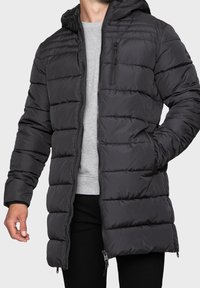 Giacca a vento nera imbottita con cappuccio, caratterizzata da sezioni trapuntate orizzontali, tasche con zip e un design di lunghezza media.