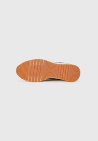 Shoe sole with a textured orange rubber finish, featuring horizontal grooves and raised sections, designed for traction and durability.