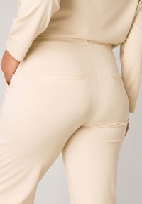 Beige joggingsbroek gemaakt van zachte stof, met een slim fit, twee achterzakken en een gladde textuur.
