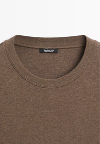 Hnědý svetr s kulatým výstřihem, žebrovaným límcem a viditelnou etiketou „Massimo Dutti Made in Portugal“ uvnitř výstřihu.