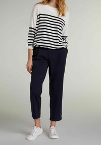 Striped sweater in white and navy, featuring 3/4 sleeves. Paired with navy trousers and white sneakers. Casual, relaxed fit, smooth texture.