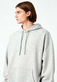 Felpa grigia chiara realizzata in tessuto morbido, con tasca frontale e cappuccio regolabile con cordino. Vestibilità ampia con un aspetto testurizzato.