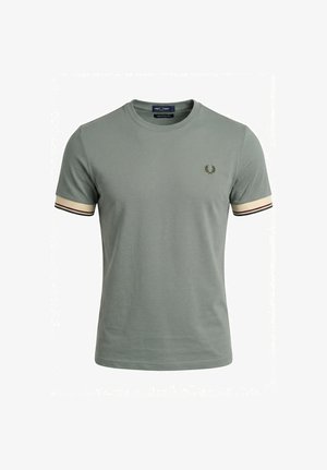 T-shirt verde chiaro a maniche corte con collo tondo, polsini beige con strisce nere e rosse, e piccolo logo di alloro ricamato sul petto.