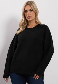 Czarny dzianinowy sweter z okrągłym dekoltem, szerokimi rękawami i ribbowanym wykończeniem. Charakteryzuje się luźnym krojem i miękką teksturą.