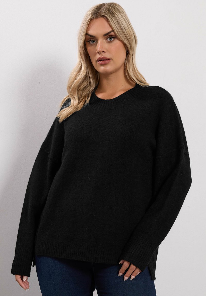 Czarny dzianinowy sweter z okrągłym dekoltem, szerokimi rękawami i ribbowanym wykończeniem. Charakteryzuje się luźnym krojem i miękką teksturą.