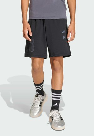 Čierne športové šortky s elastickým pásom, zdobené textúrovaným grafickým dizajnom. Spárované s čiernymi a bielymi pruhovanými ponožkami a striebornými topánkami.