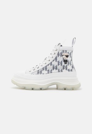 Sneakers alte con suola in gomma bianca, dettagli traslucidi e un motivo geometrico grigio. Presentano un dettaglio di personaggio dei cartoni animati sul lato.