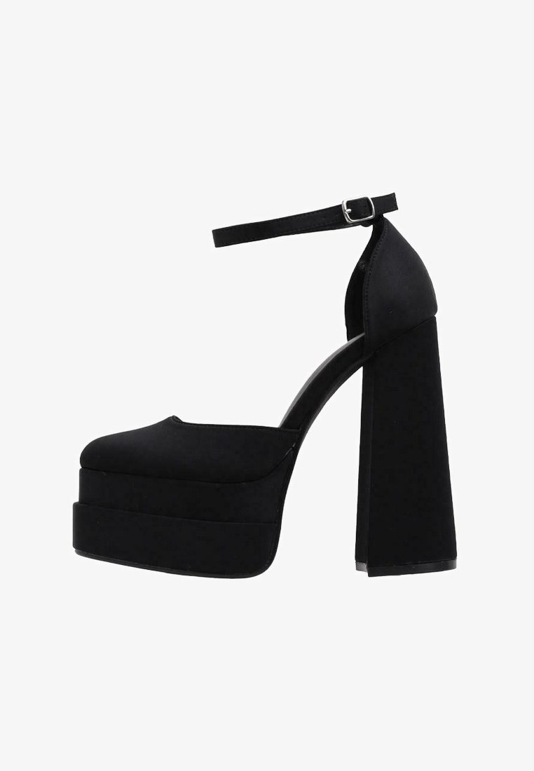 Zapatos de tacón alto negros con plataforma y correa en el tobillo, con una textura suave, punta redondeada y un tacón grueso.